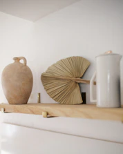 Handcrafted ceramic vase with natural textures on a simple white shelf.
