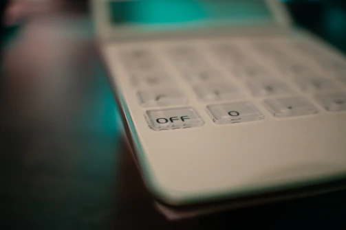 A sleek, modern calculator on a clean white desk with soft natural light