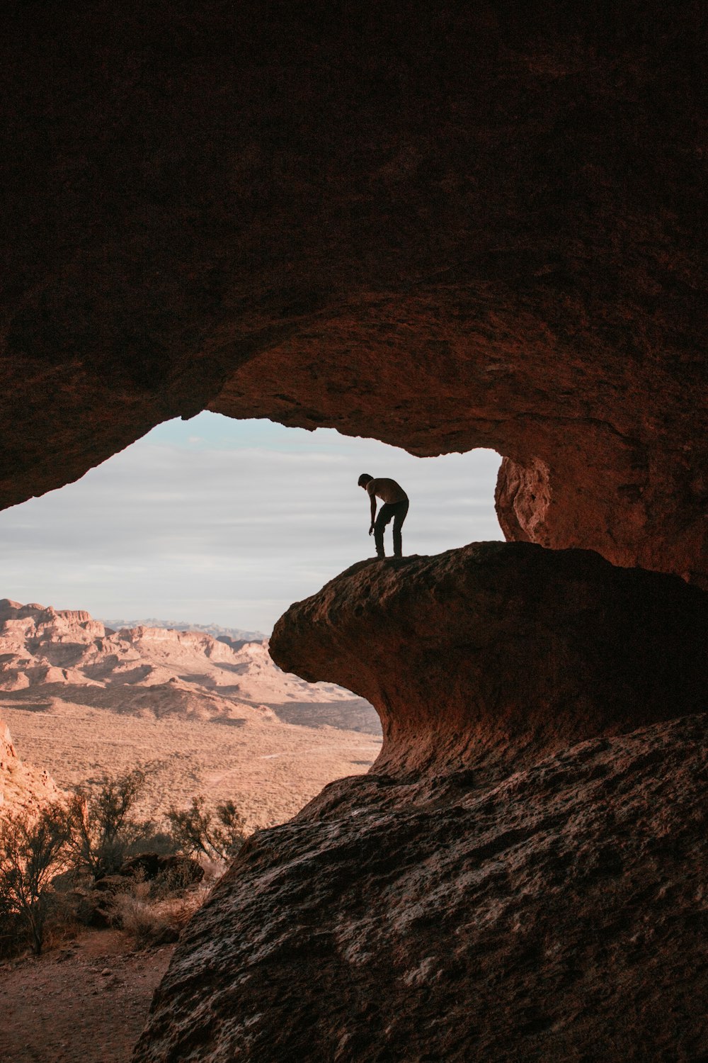 silhouette of person standing on rock formation during daytime