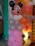 A decorative balloon arrangement resembling a cartoon character with a large head featuring black ears and a smiling face. The balloons are predominantly pink with white polka dots, accompanied by others in pastel shades. The background includes more balloons in orange, pink, and white colors.