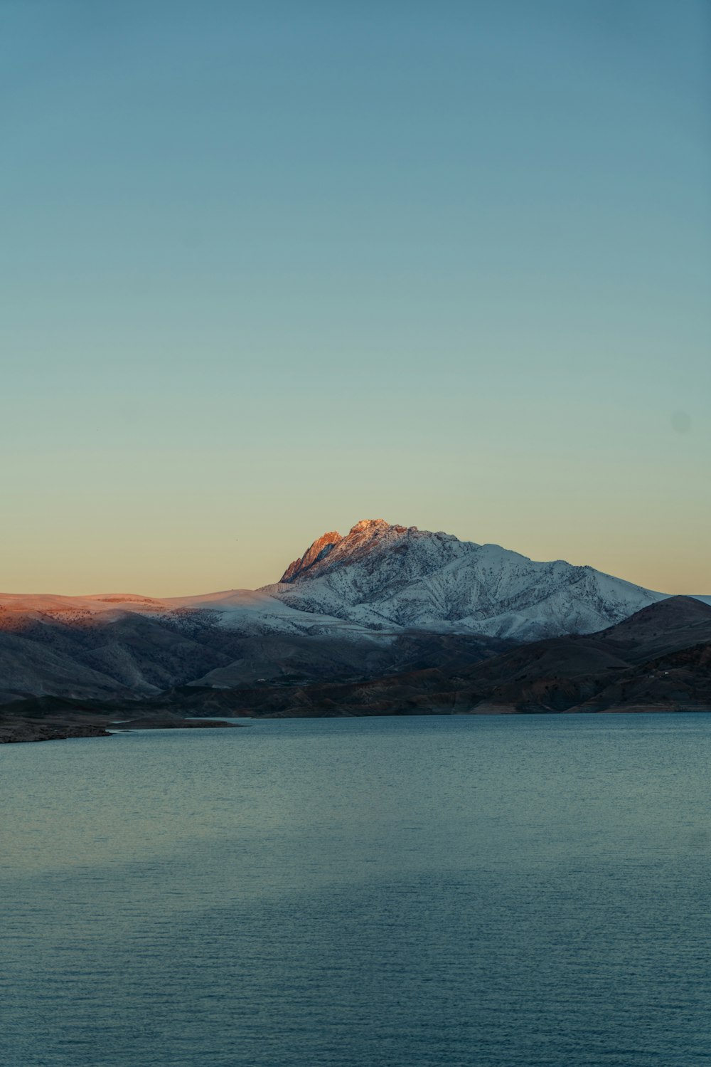 brown and black mountains near body of water during daytime