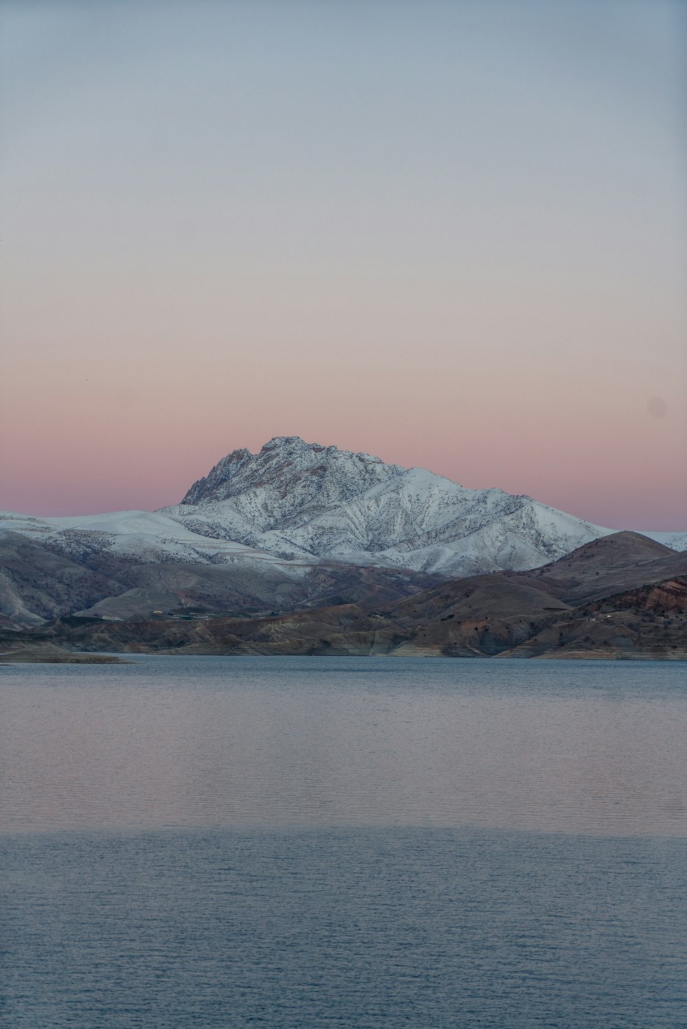 snow covered mountain near body of water during daytime