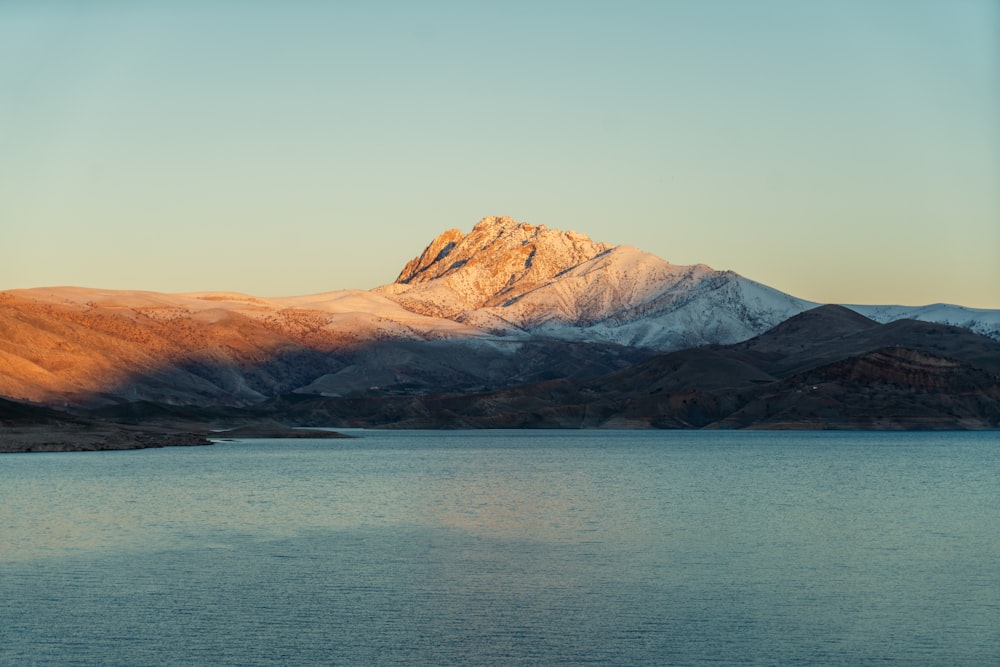 brown and white mountains beside body of water during daytime