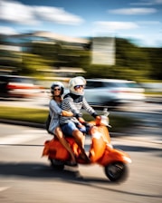 man in black jacket riding orange motor scooter on road during daytime