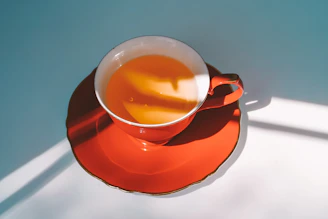 A pair of warm orange stoneware cups catching the afternoon sun on a windowsill.