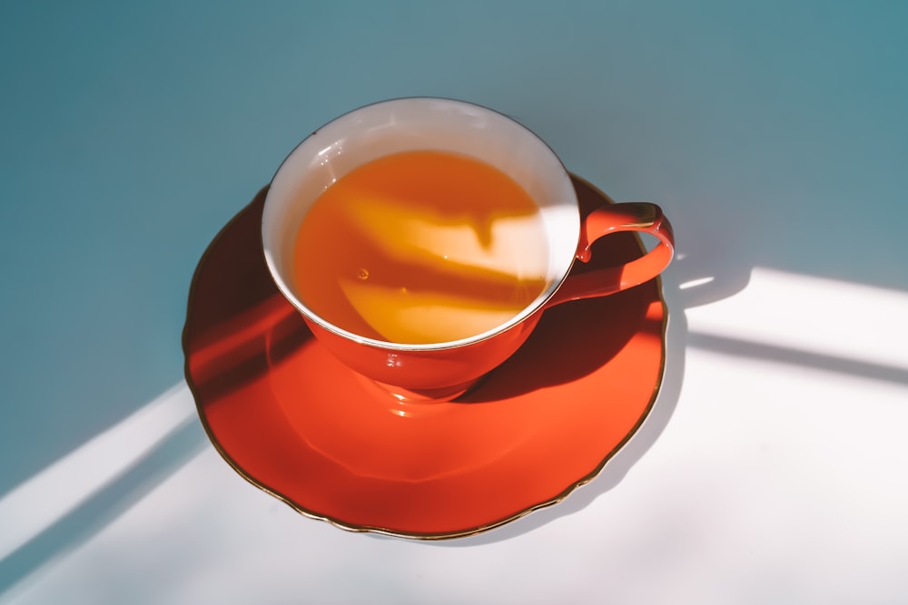 red ceramic teacup on red saucer