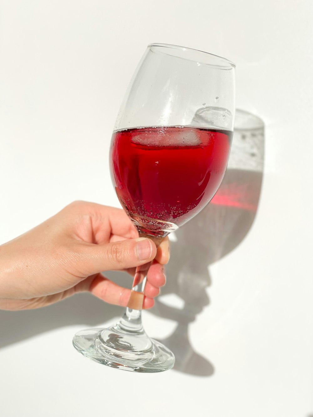 person holding clear wine glass with red wine