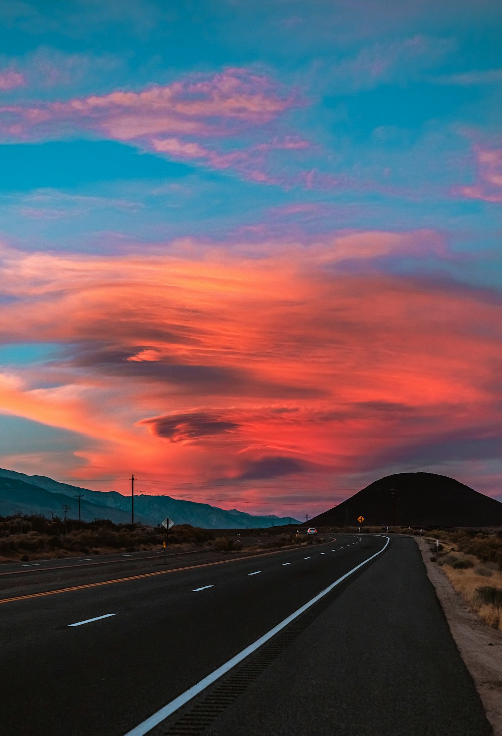 gray asphalt road under orange and blue sky