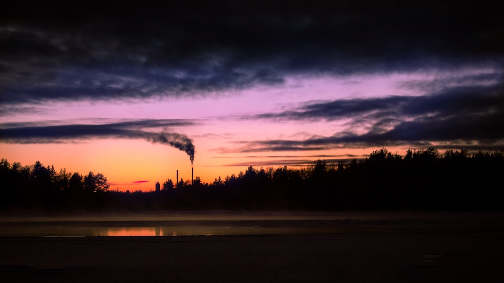 silhouette of trees under cloudy sky during sunset