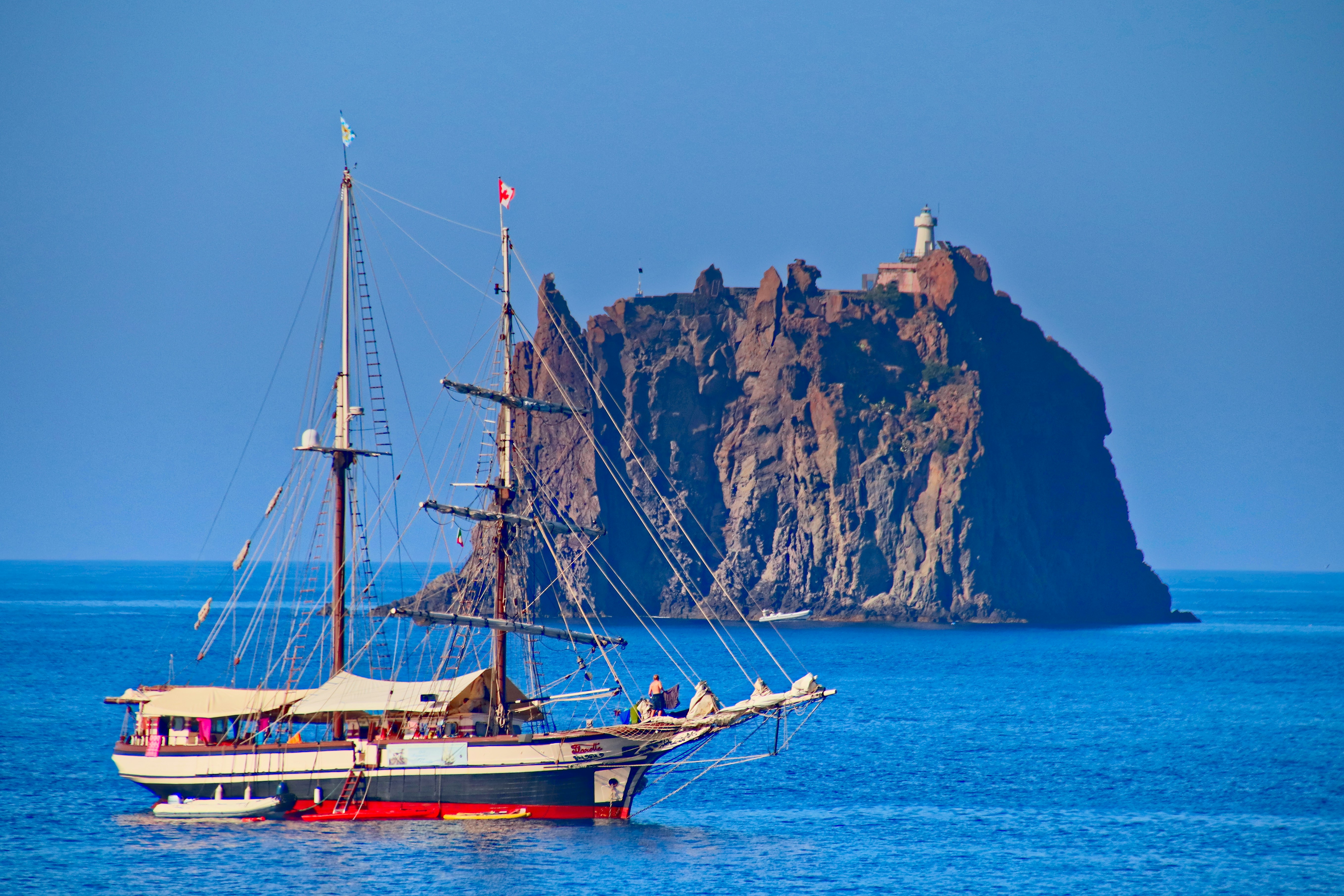 brown boat on sea near brown mountain during daytime