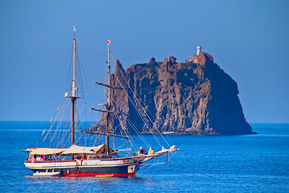 brown boat on sea near brown mountain during daytime