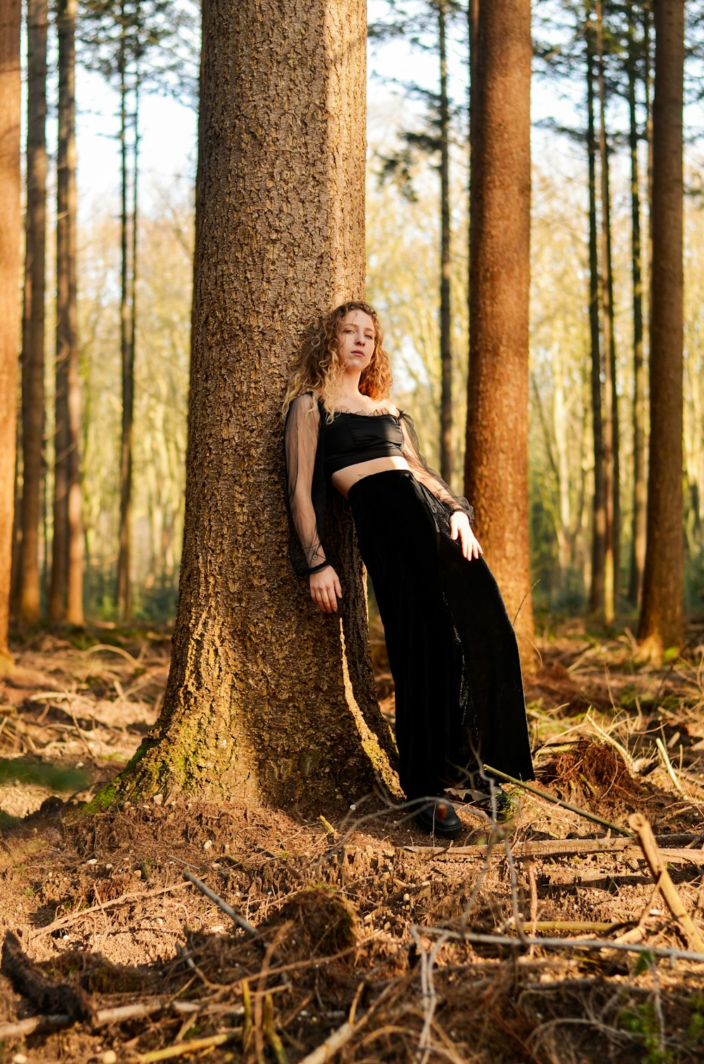 woman in black dress standing beside brown tree