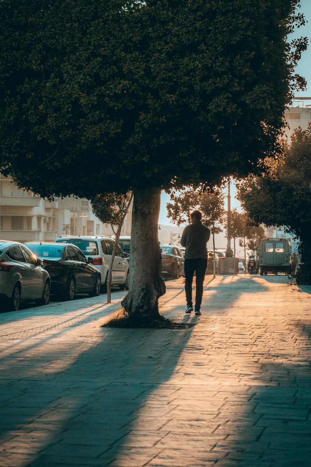 man in black jacket walking on sidewalk during daytime