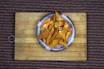 Close-up of golden, crispy traditional Indian snack pieces arranged invitingly on a rustic wooden platter.