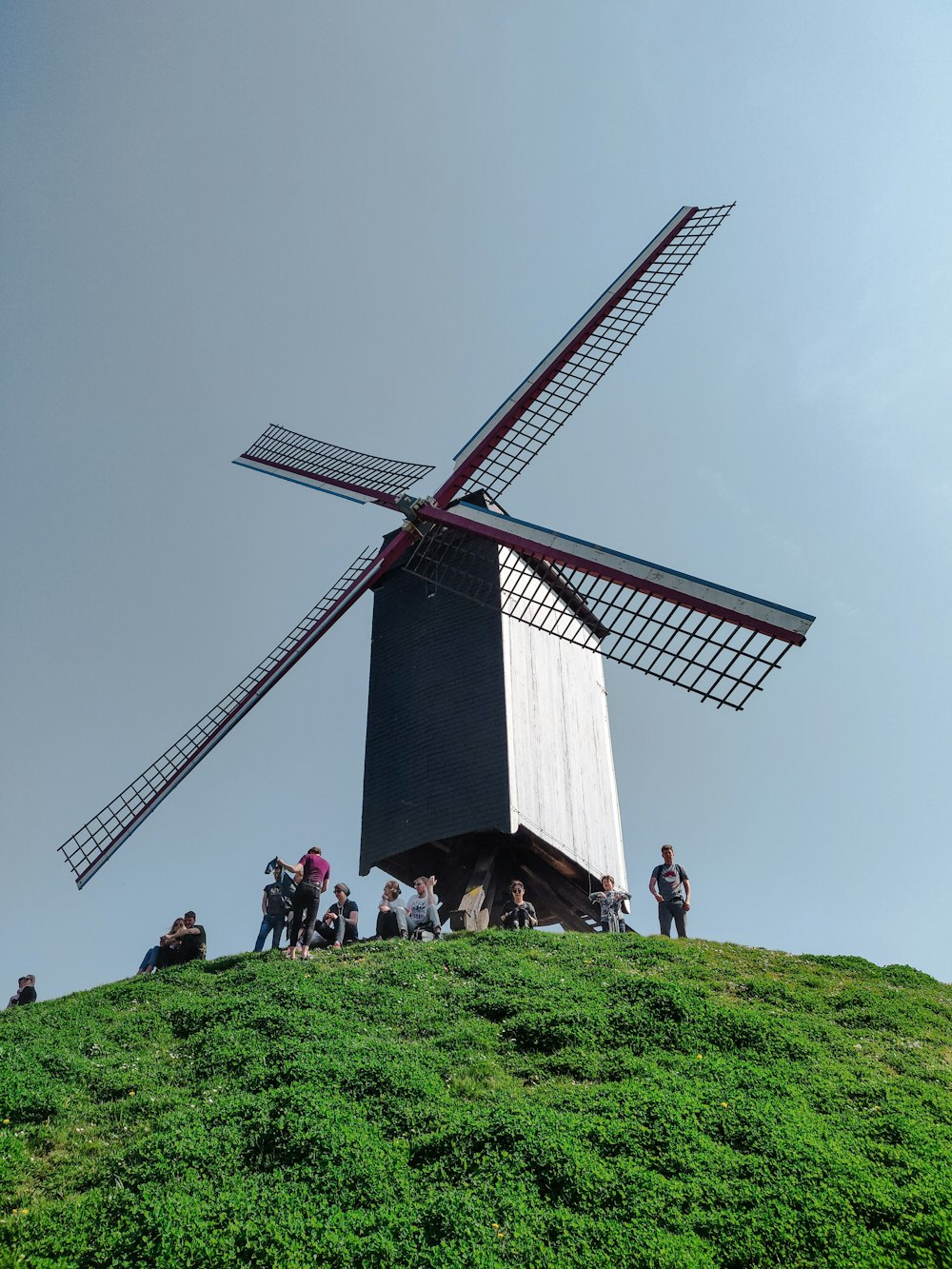 people standing on green grass field near brown and white windmill during daytime