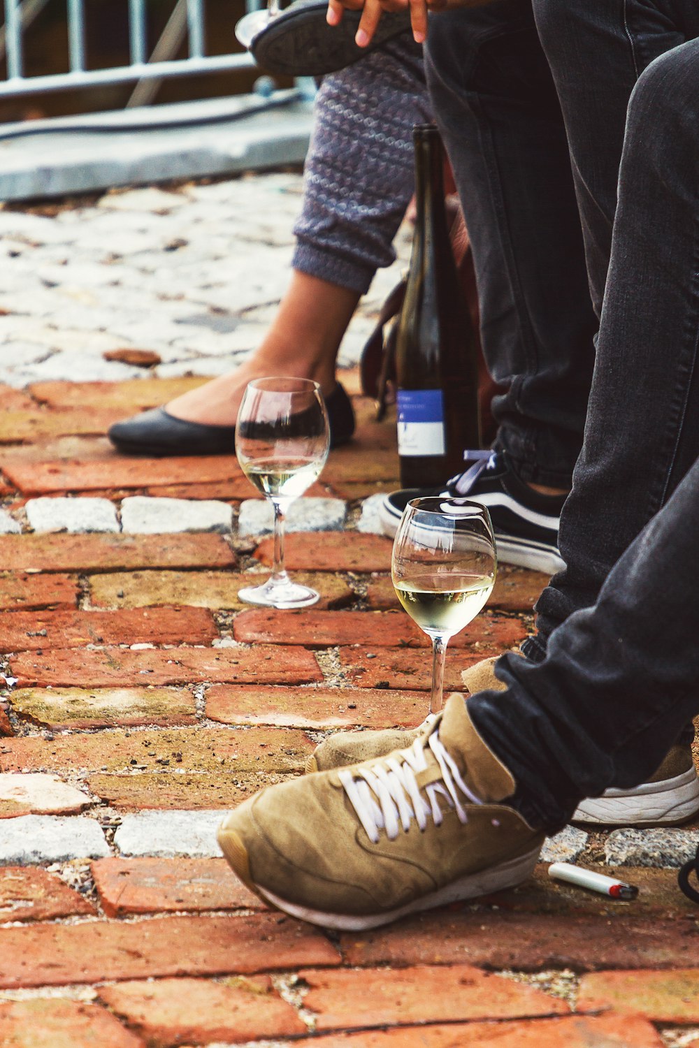 person in blue denim jeans and brown shoes sitting on brown brick floor