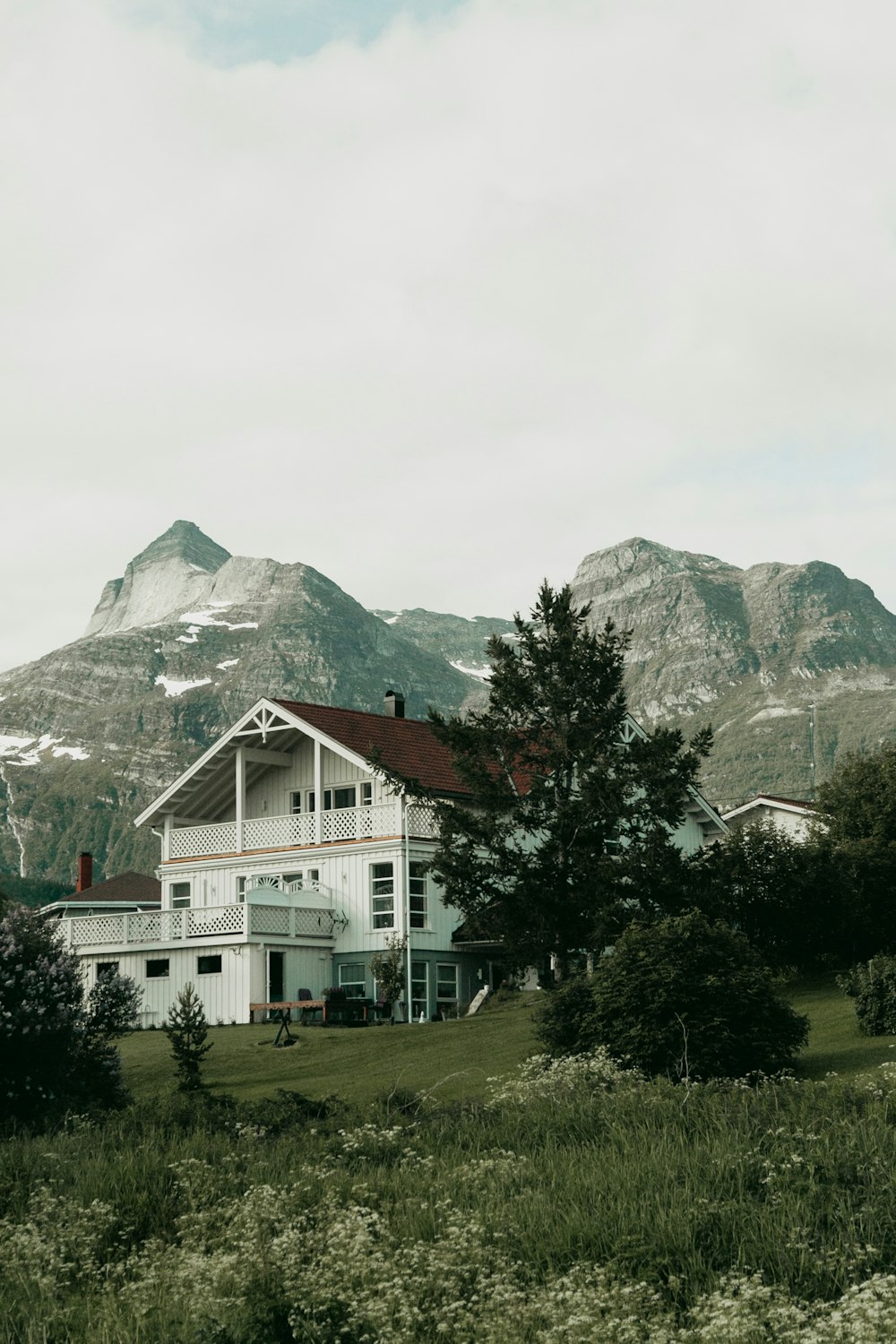 white and red house near green trees and mountain during daytime