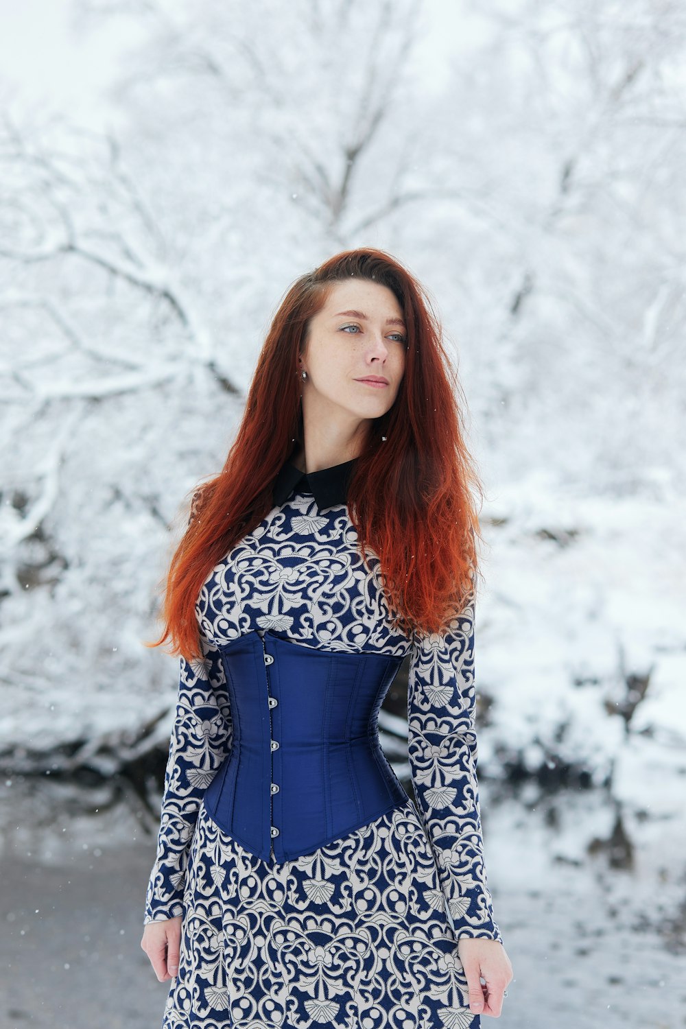Frau in schwarz-weißem langärmeligem Kleid, die tagsüber auf schneebedecktem Boden steht