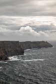 A dramatic ocean storm crashing against rugged Vancouver Island cliffs under a moody sky.