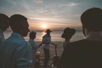silhouette of people standing on seashore during sunset