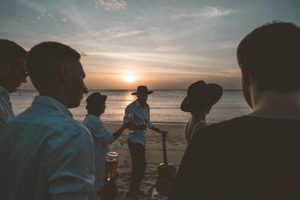 silhouette of people standing on seashore during sunset