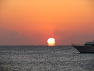 A vibrant sunset over the Mediterranean Sea with a luxury yacht anchored near the Tunisian coast.