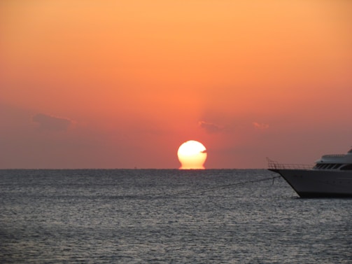 A vibrant sunset over the Mediterranean Sea with a luxury yacht anchored near the Tunisian coast.
