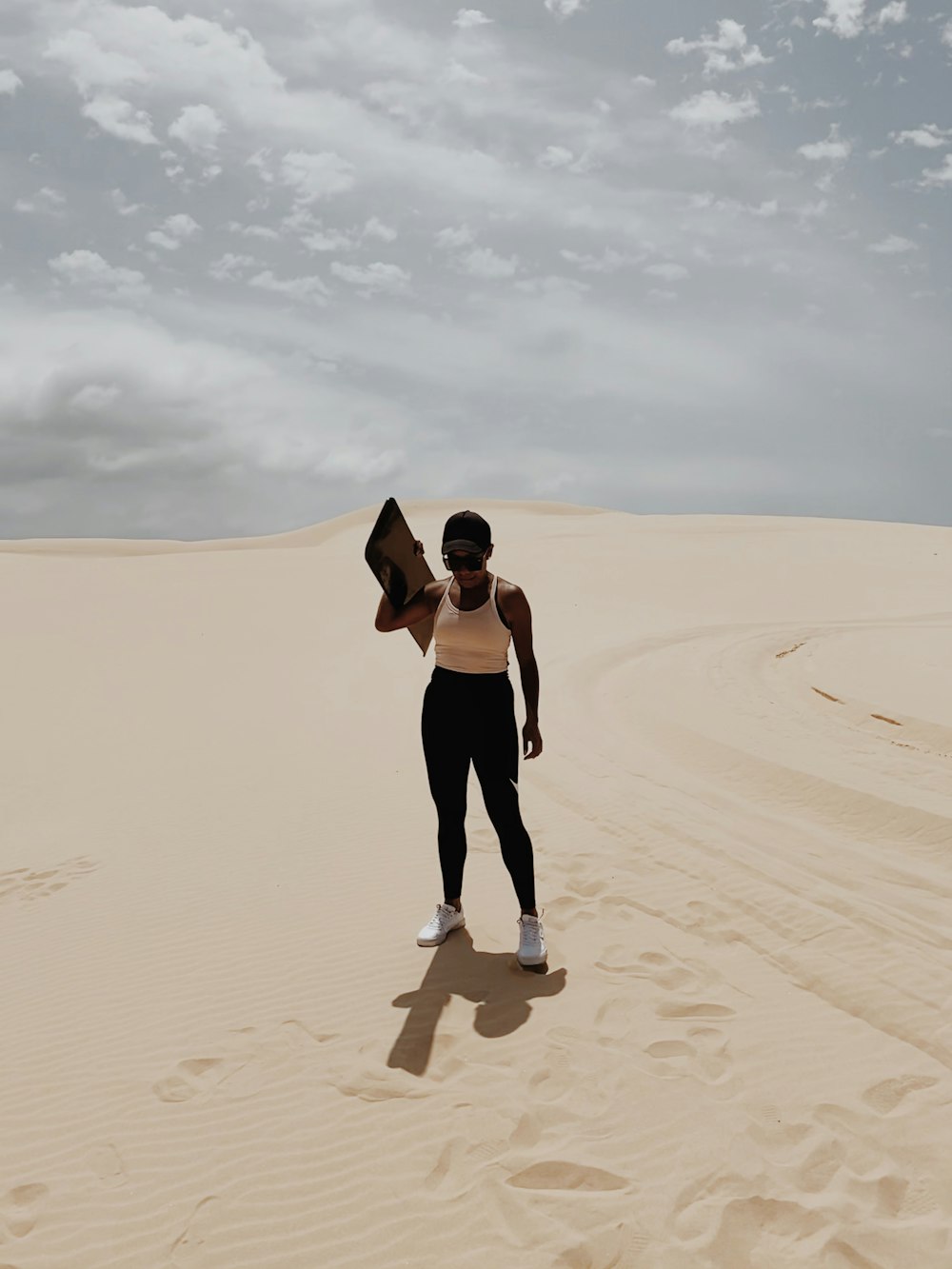 woman in black tank top and black pants walking on sand during daytime