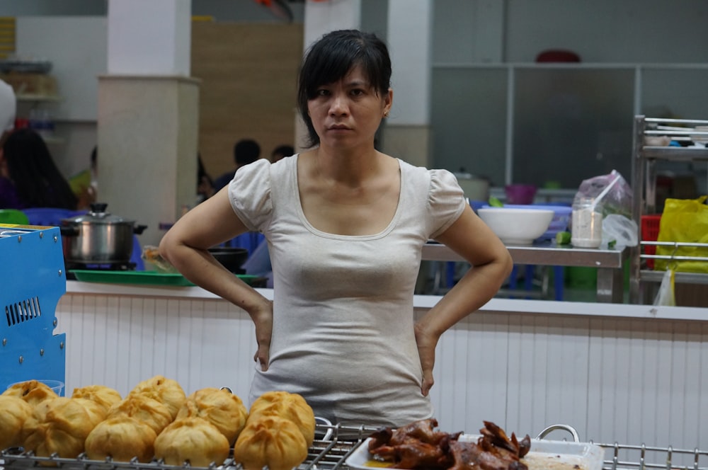 woman in white scoop neck shirt standing in front of baked bread