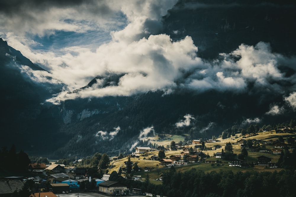 white and black houses near mountain under white clouds during daytime