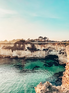 brown rock formation beside blue sea under white sky during daytime