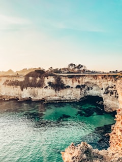brown rock formation beside blue sea under white sky during daytime
