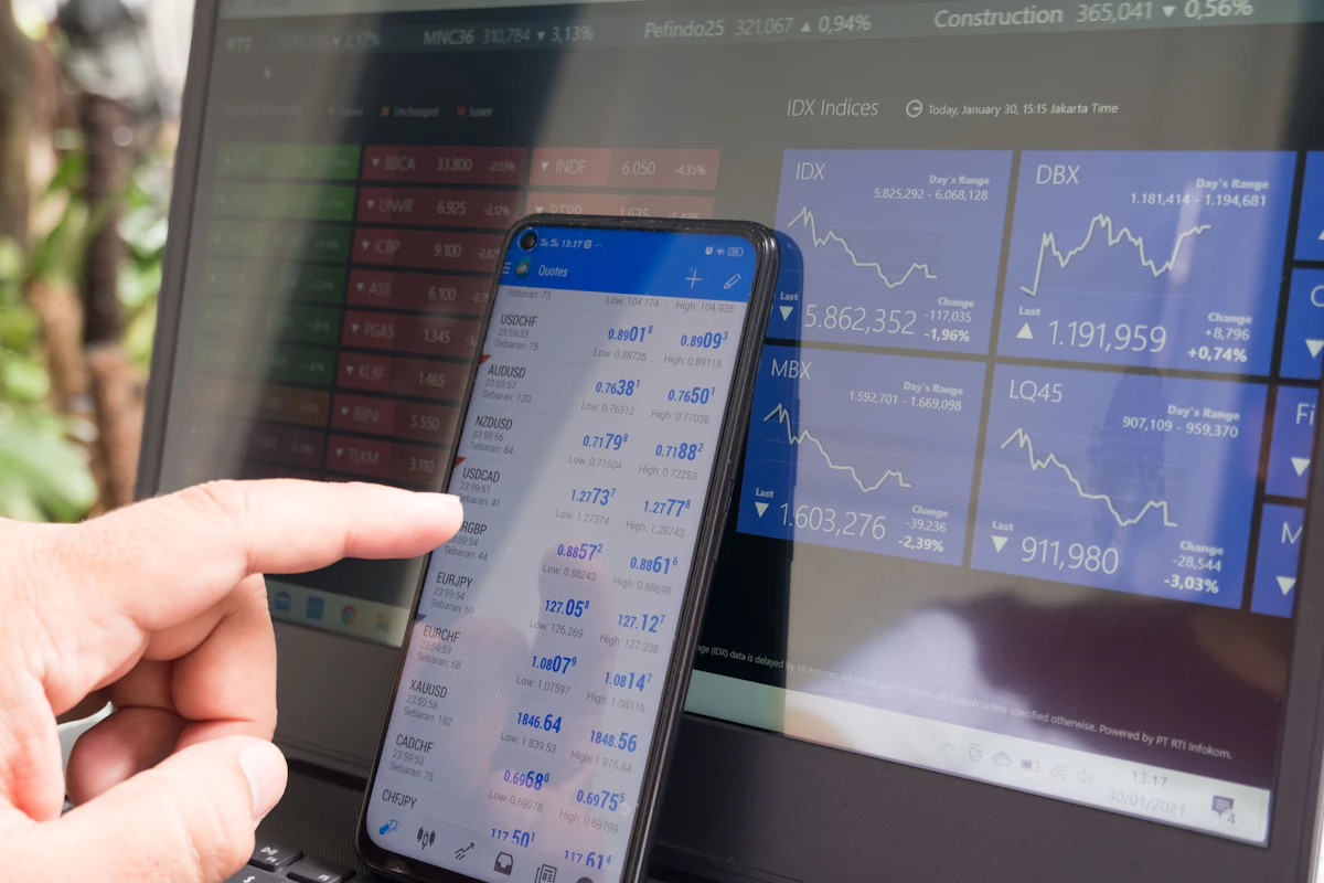 Smartphone displaying forex trading data beside a laptop representing mobile-accessible TradingView webhook automation