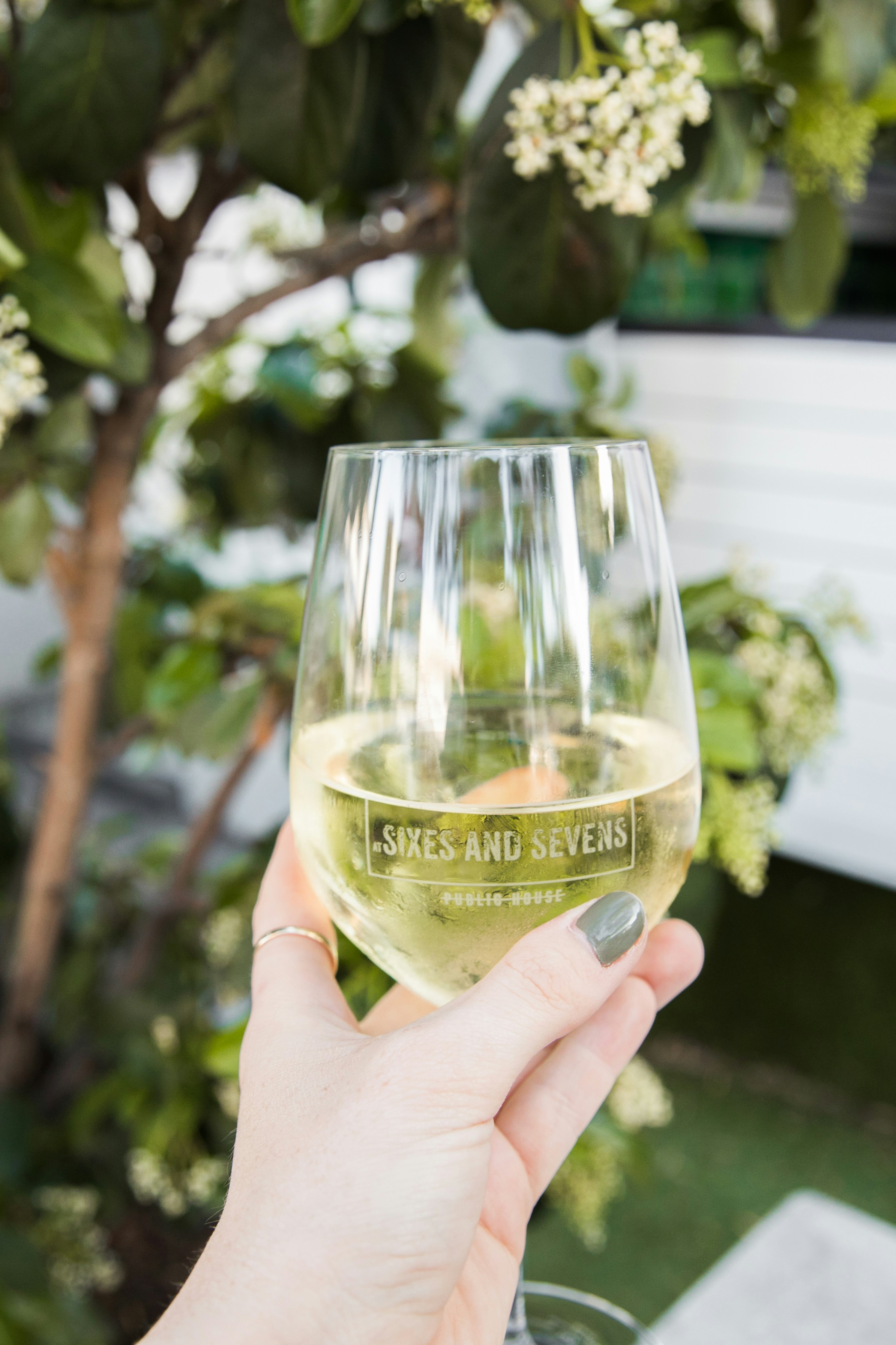 person holding clear wine glass with green liquid