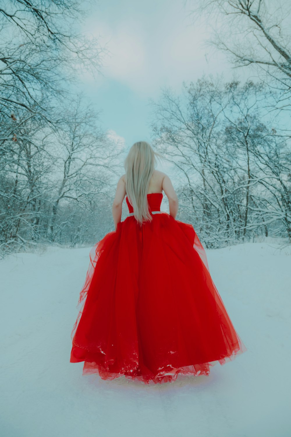 woman in red dress standing on snow covered ground during daytime