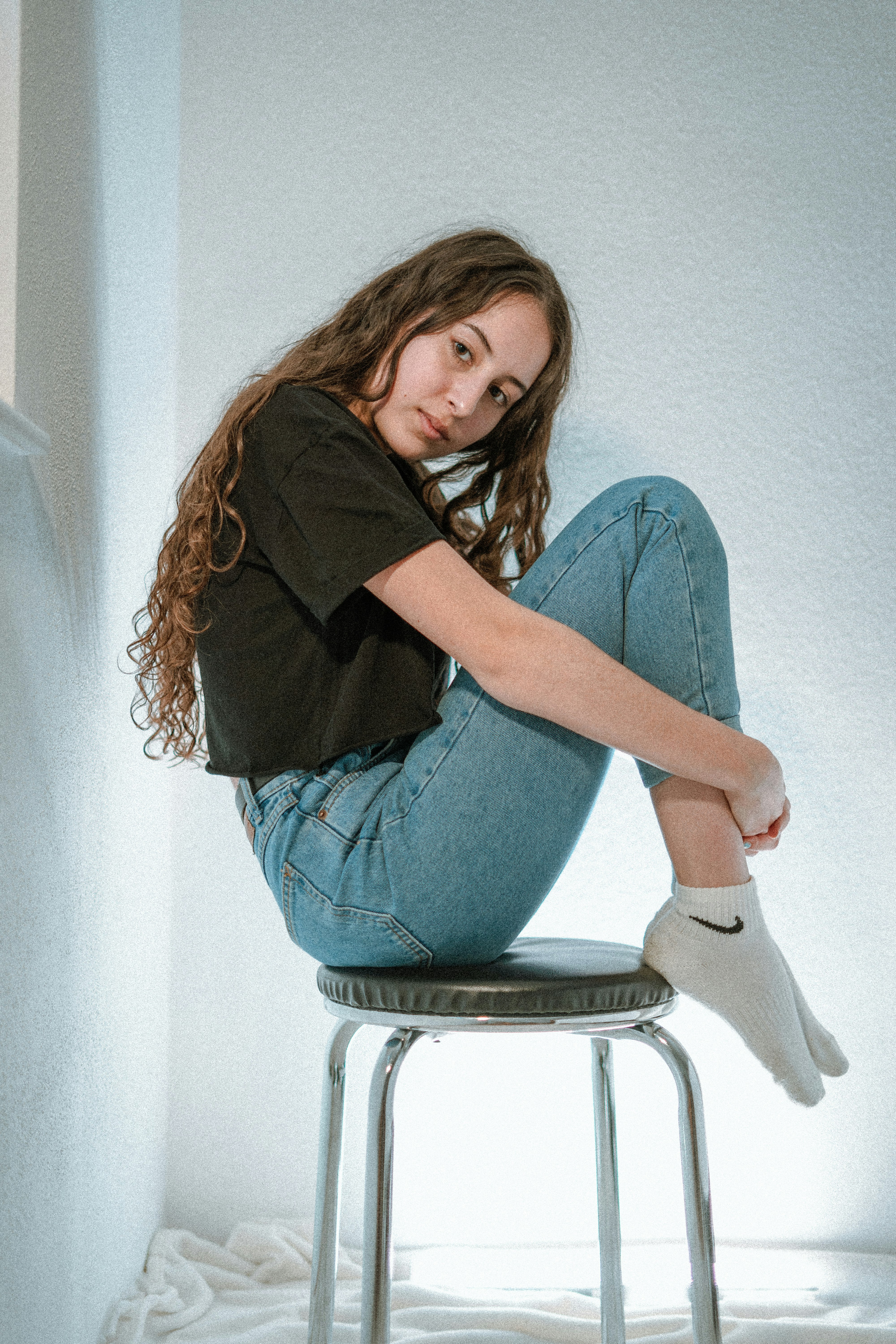 woman in black long sleeve shirt and blue denim jeans sitting on white chair