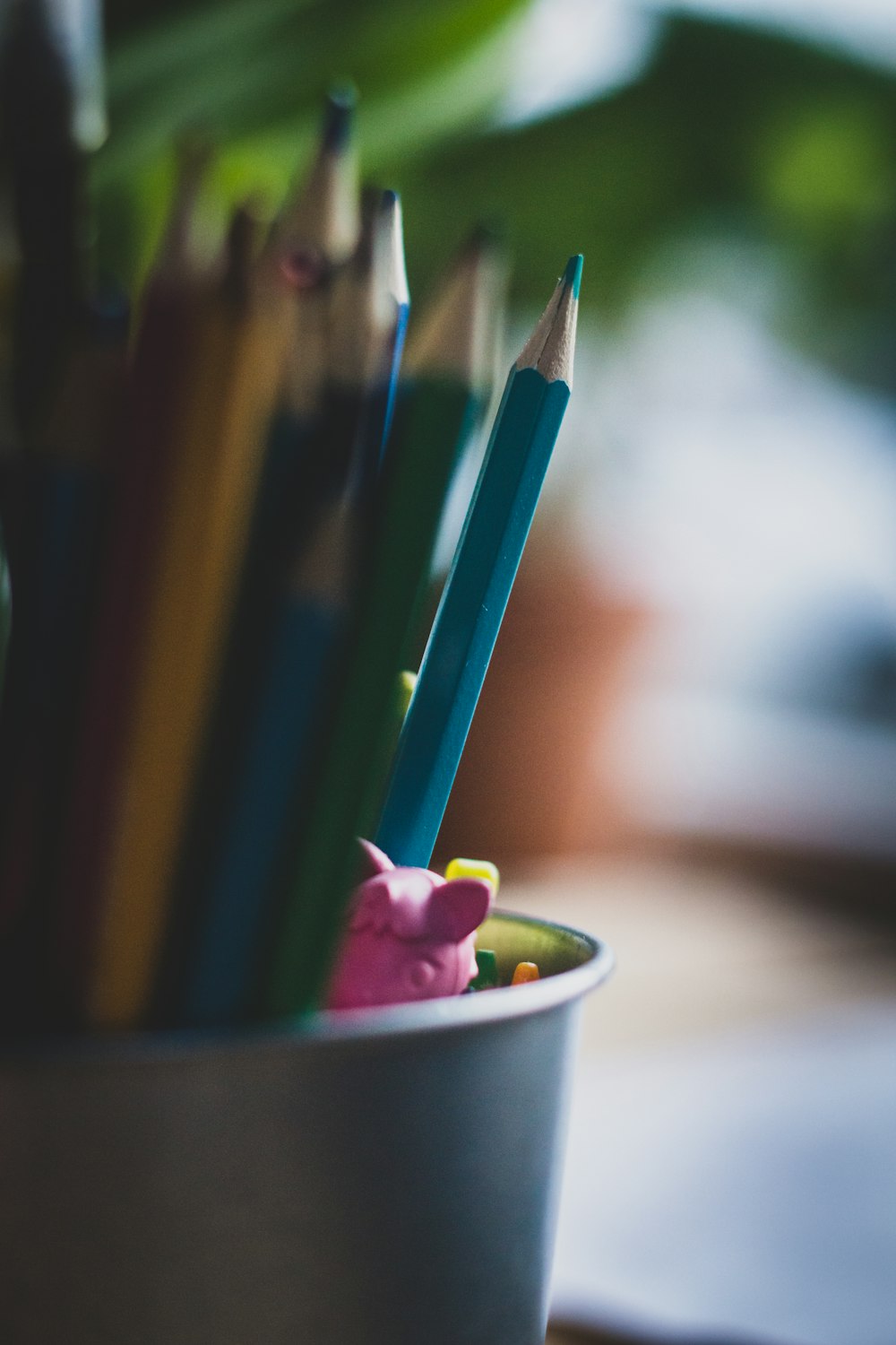 pink yellow green and blue coloring pencils in white ceramic cup