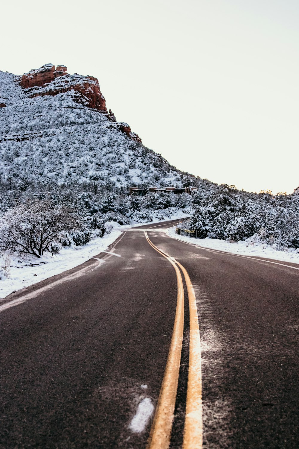 gray asphalt road between white and brown rocky mountain during daytime