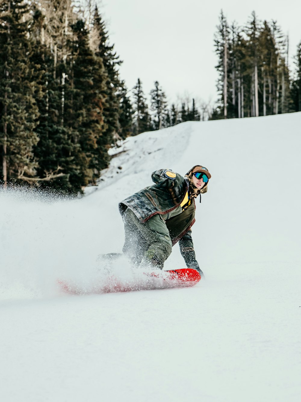 person in black and white jacket riding red snowboard on snow covered ground during daytime