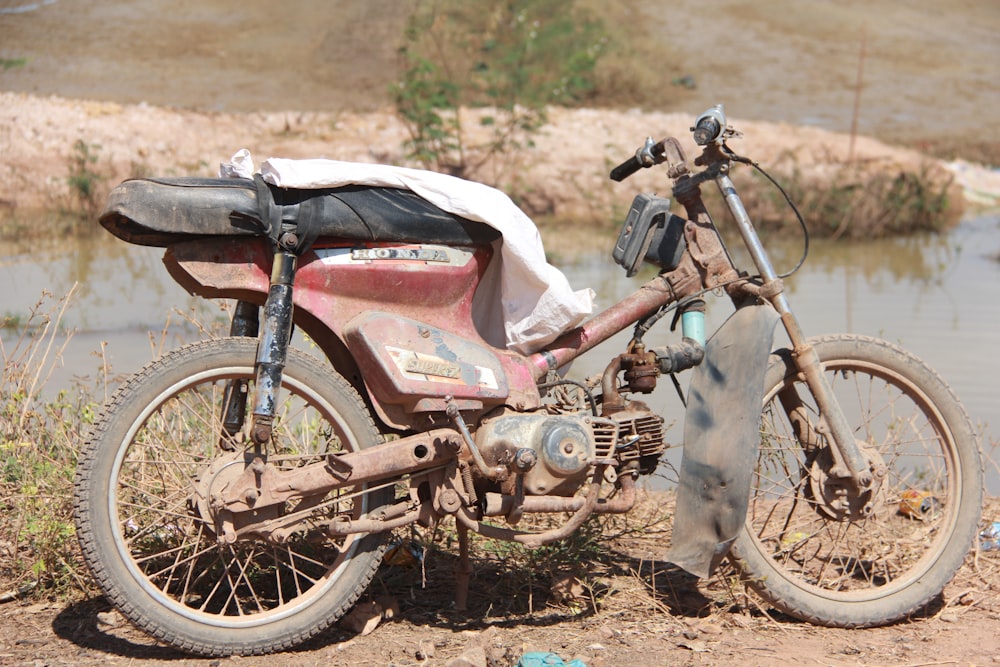 red and black motorcycle on dirt road during daytime