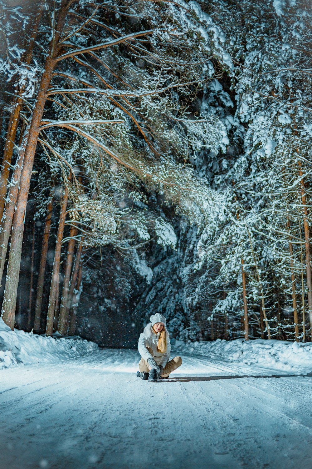 woman in white coat sitting on snow covered ground