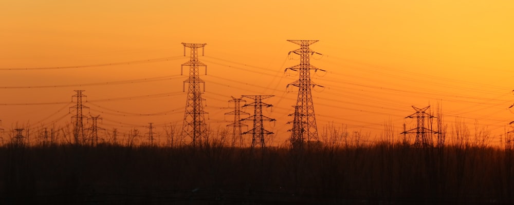 silhouette of electric towers during sunset