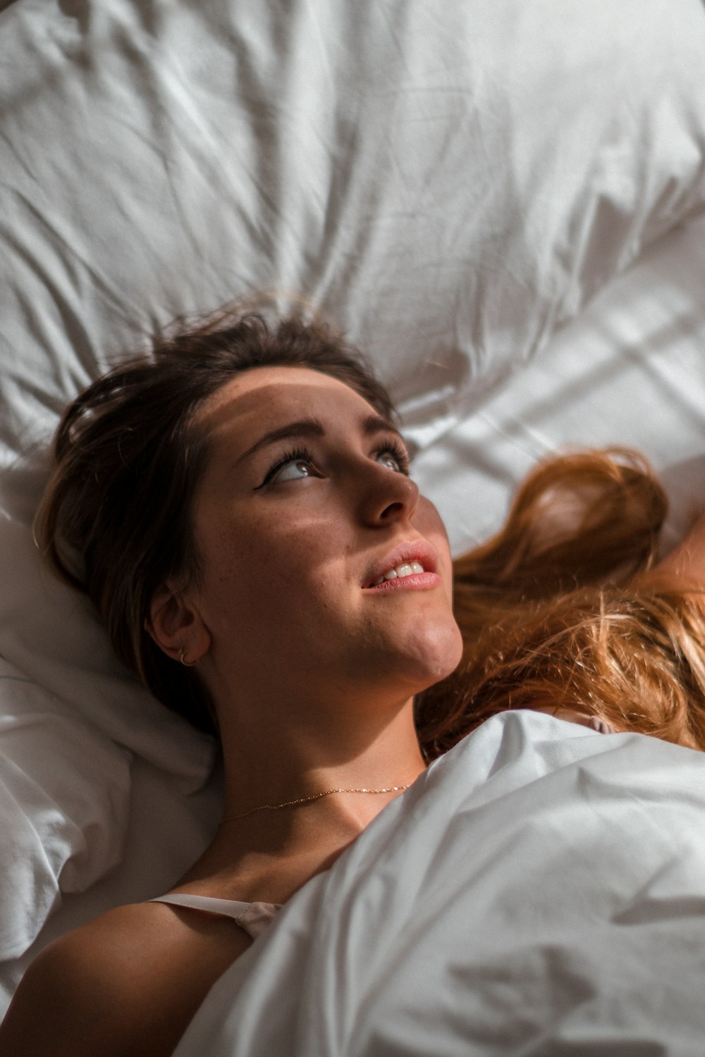 woman in white shirt lying on bed