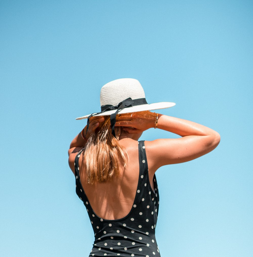 woman in black and white polka dot tank top wearing white fedora hat