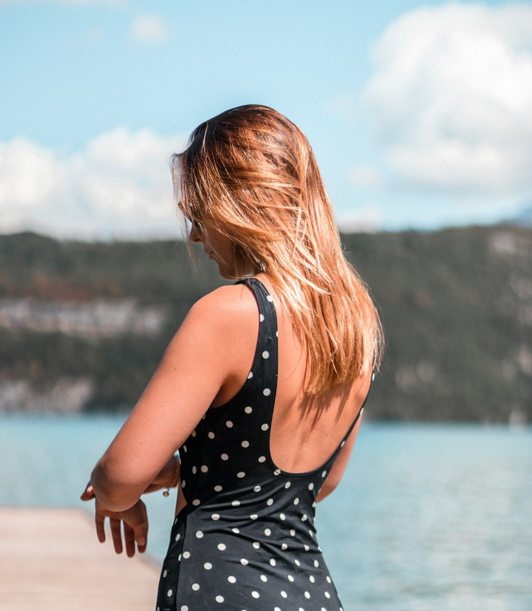 woman in black and white polka dot tank top standing on seashore during daytime