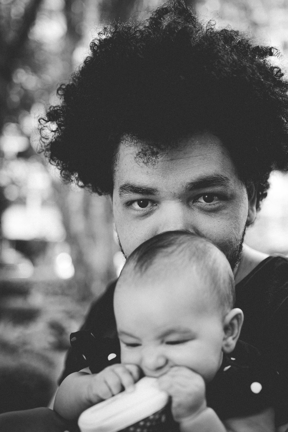 Graustufenfoto eines Mannes, der ein Baby trägt