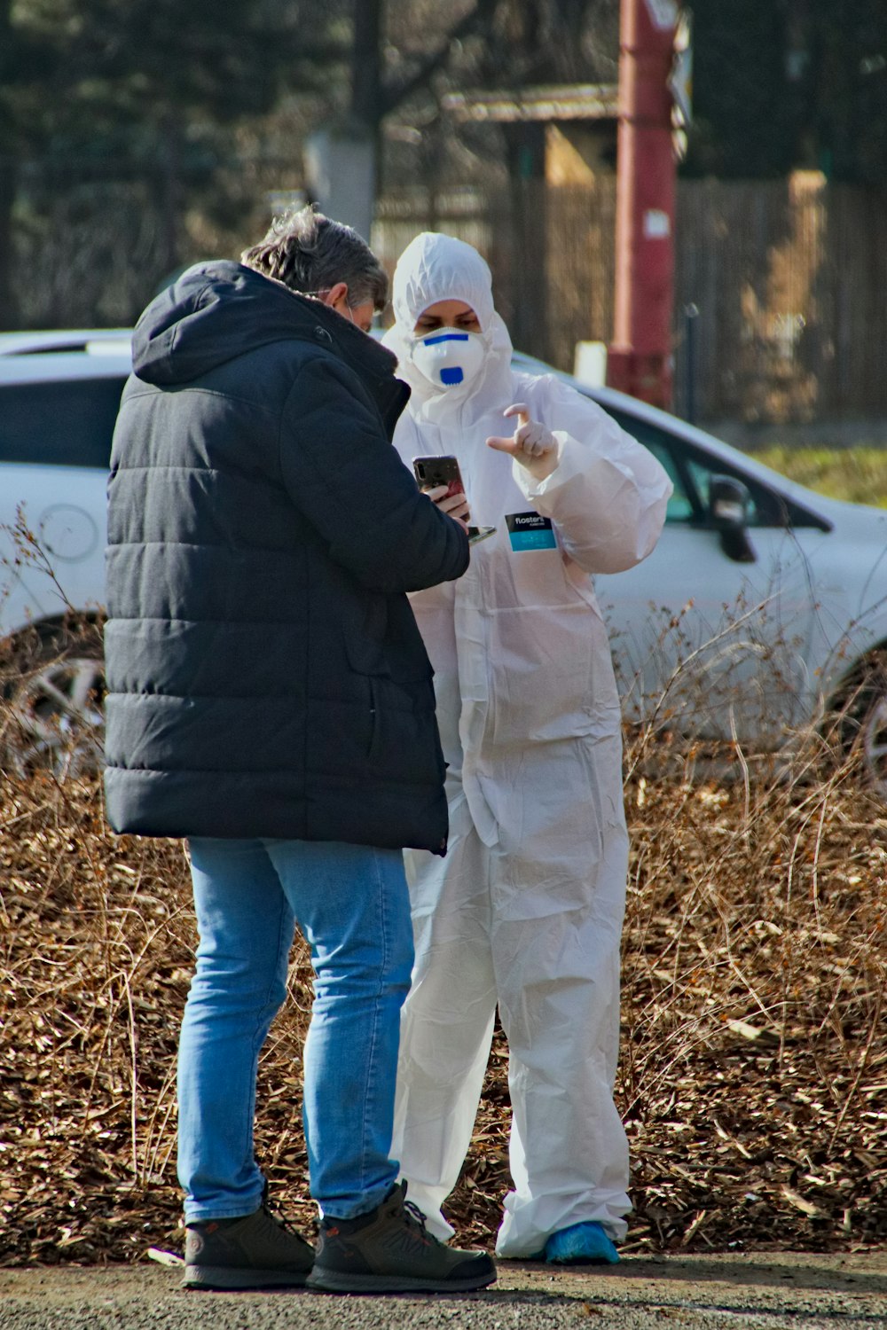 man in black jacket and blue denim jeans standing beside woman in white jacket