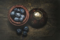 A rustic wooden bowl filled with fresh fruit on a wooden table.