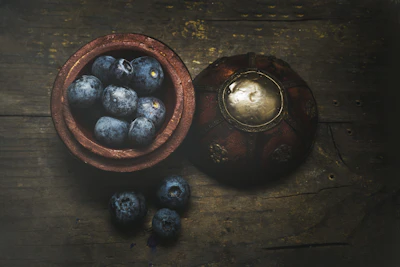 A basket overflowing with freshly picked blueberries sitting on a rustic wooden table