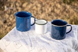 blue ceramic mugs on white table cloth